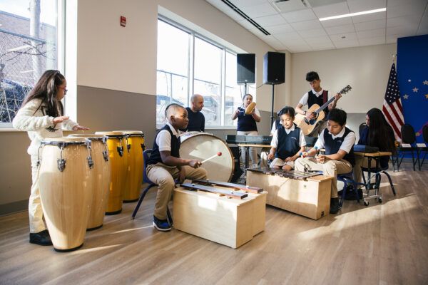 Students playing different musical instruments in a classroom studio.